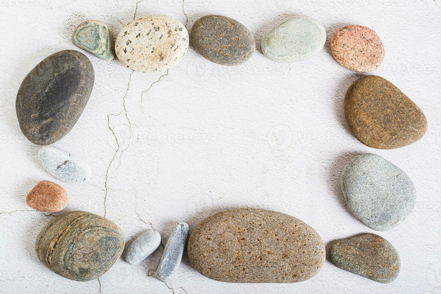 Template frame made of smooth sea stones on a light background top view photo