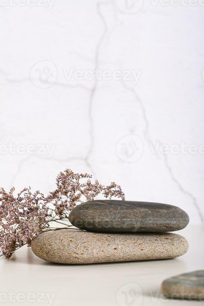 Pattern of smooth flat sea stones and dried flowers on the table vertical view photo