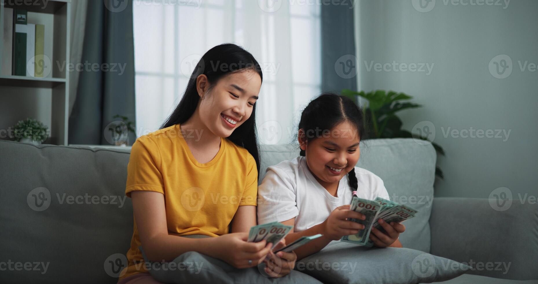retrato de joven mujer y adolescente niña contando efectivo dinero en sofá en el vivo habitación a en casa, feliz contando dolares billete foto