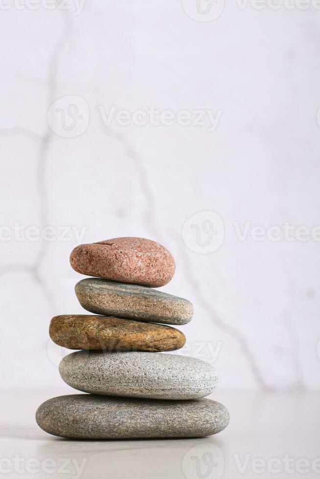 Pyramid of smooth sea stones on a table on the background of a plastered wall vertical view photo