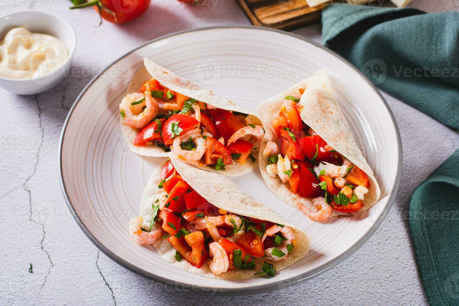 Soft appetizer mini tacos with shrimp, tomatoes and herbs on a plate photo