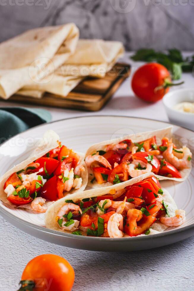 Vegetarian mini tacos with tomatoes, shrimp and herbs on a plate on the table vertical view photo