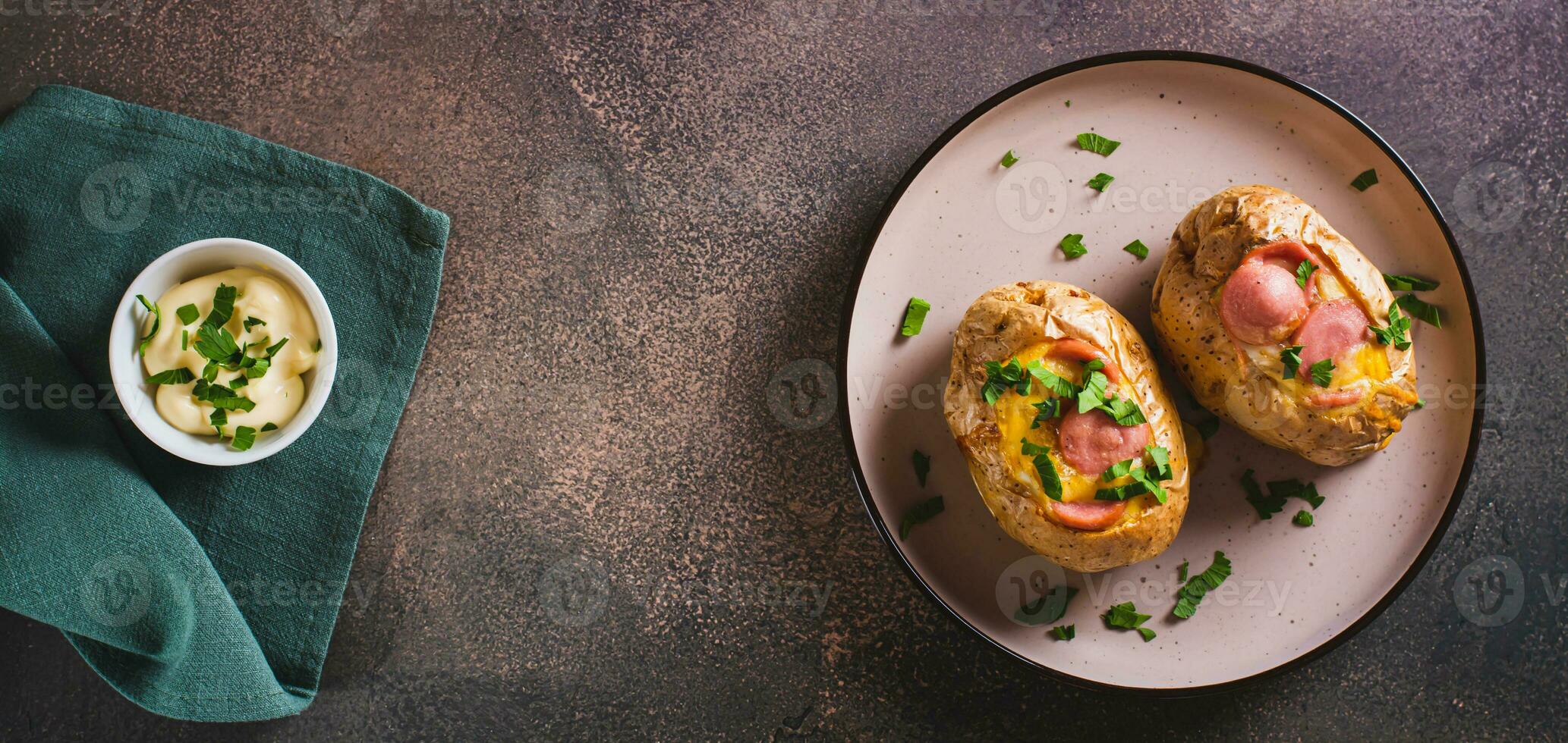 Baked potatoes in skins with egg and pieces of sausage on a plate on the table top view web banner photo