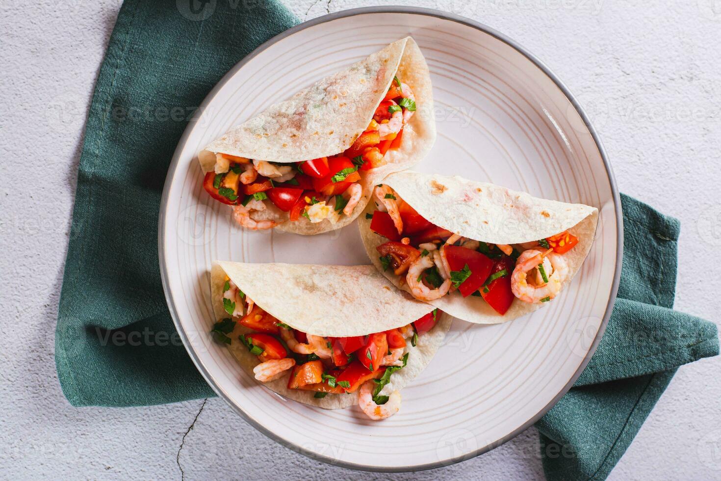 Close up of vegetarian mini tacos with tomatoes, shrimp and herbs on a plate top view photo