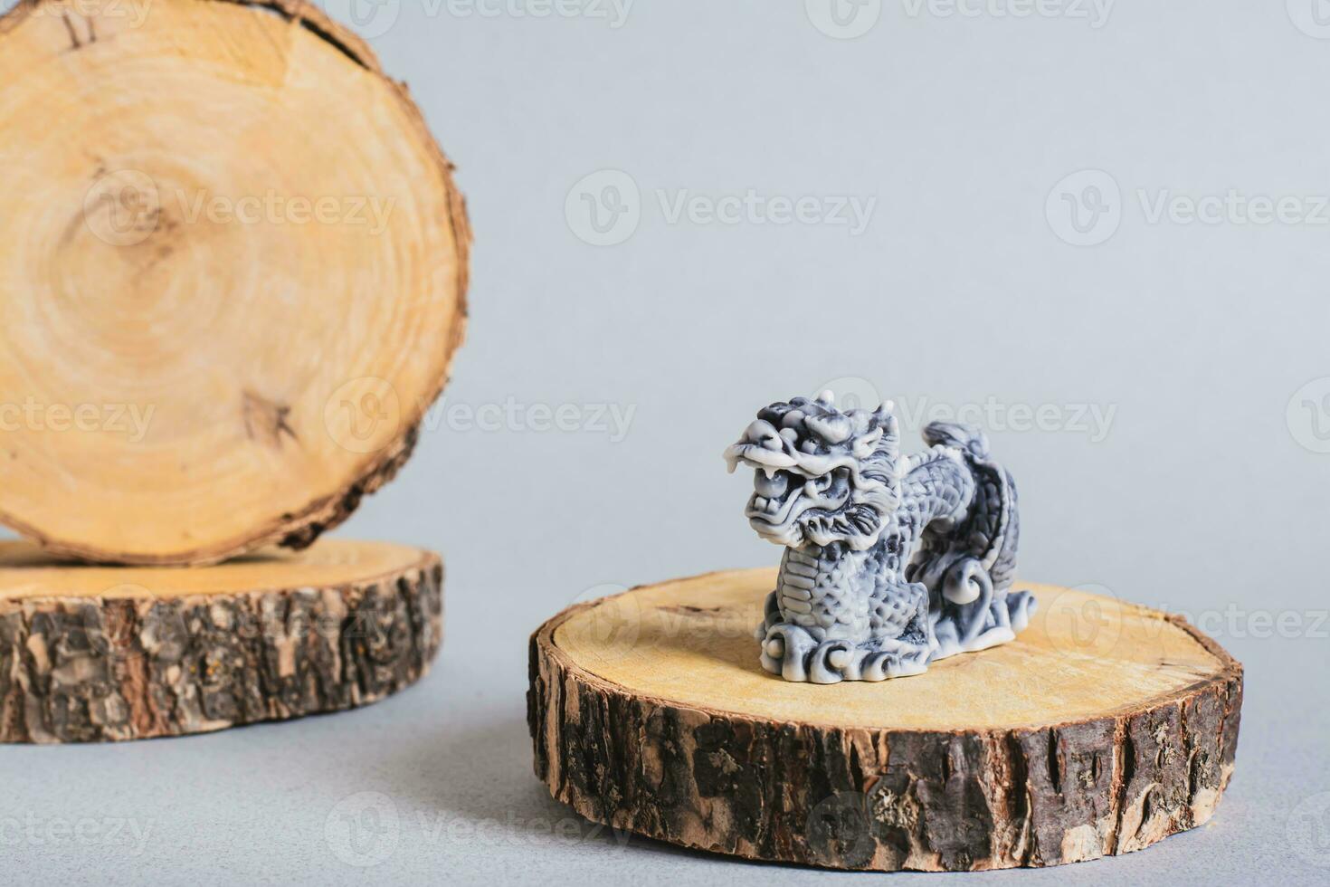 Ceramic dragon on tree trunk slices on gray background for Chinese New Year photo