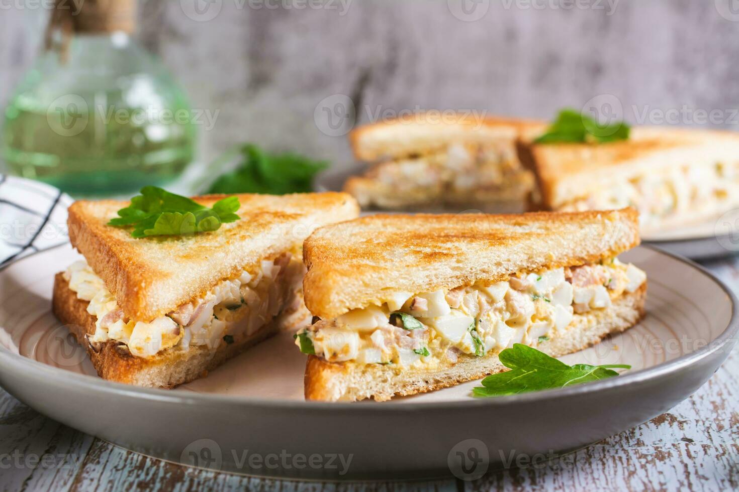 Chopped sandwiches with egg, bacon and herbs salad on a plate on the table photo