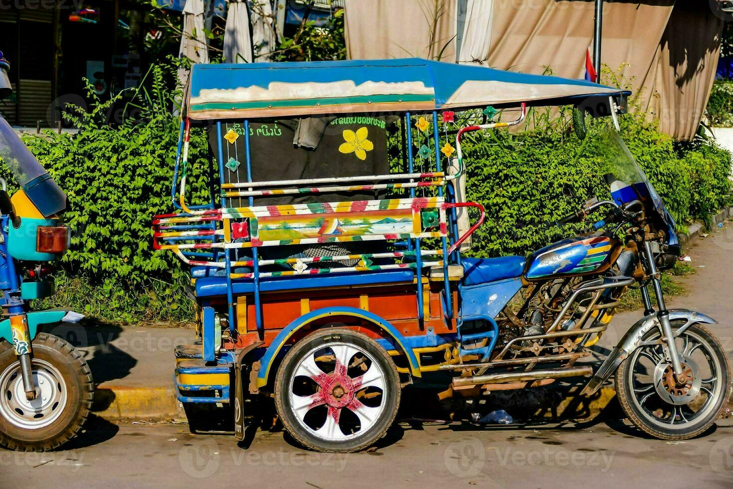 un vistoso tuk tuk estacionado en el lado de el la carretera foto