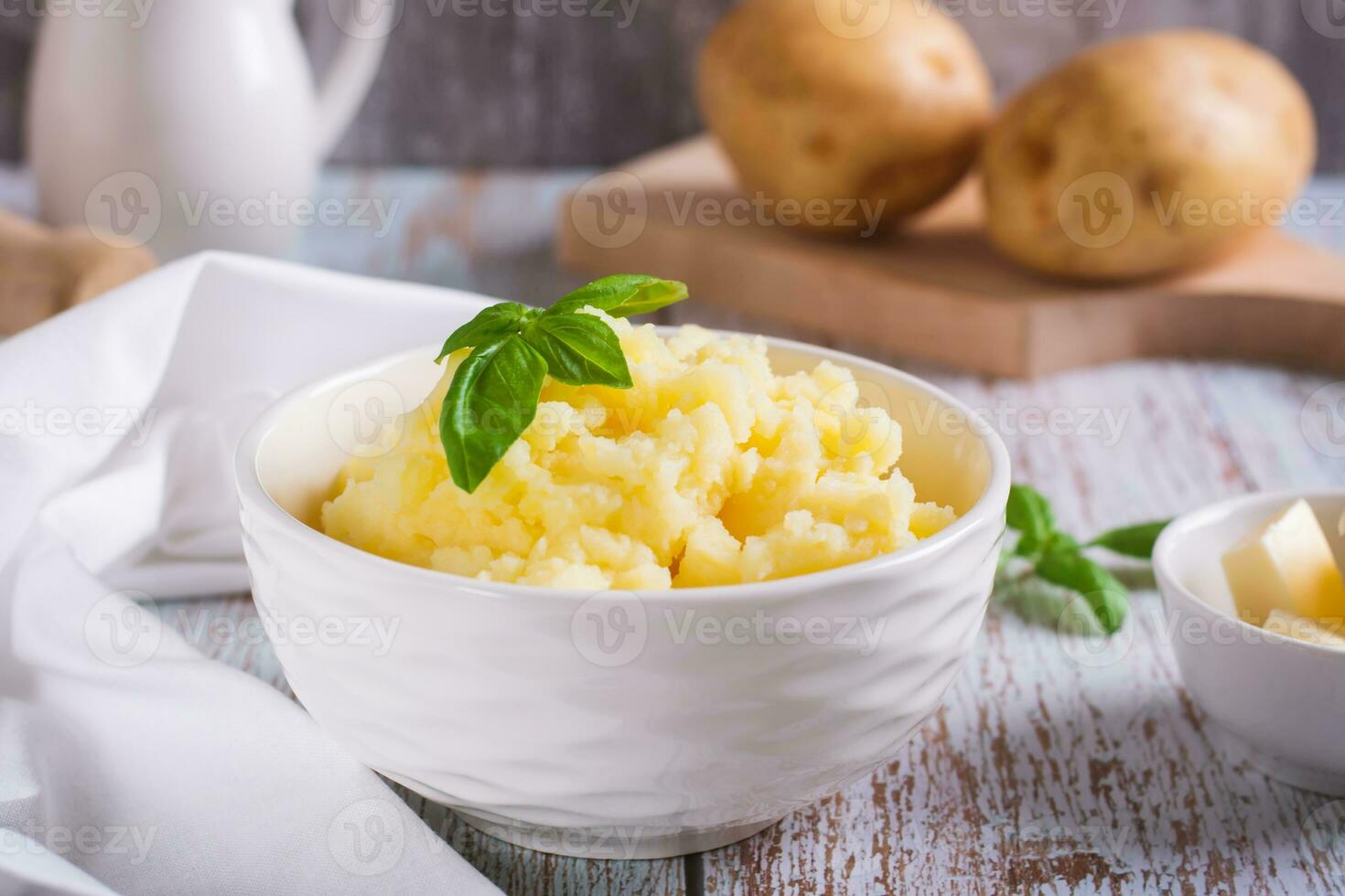 Fresco machacado patatas y albahaca hojas en un cuenco en el mesa foto