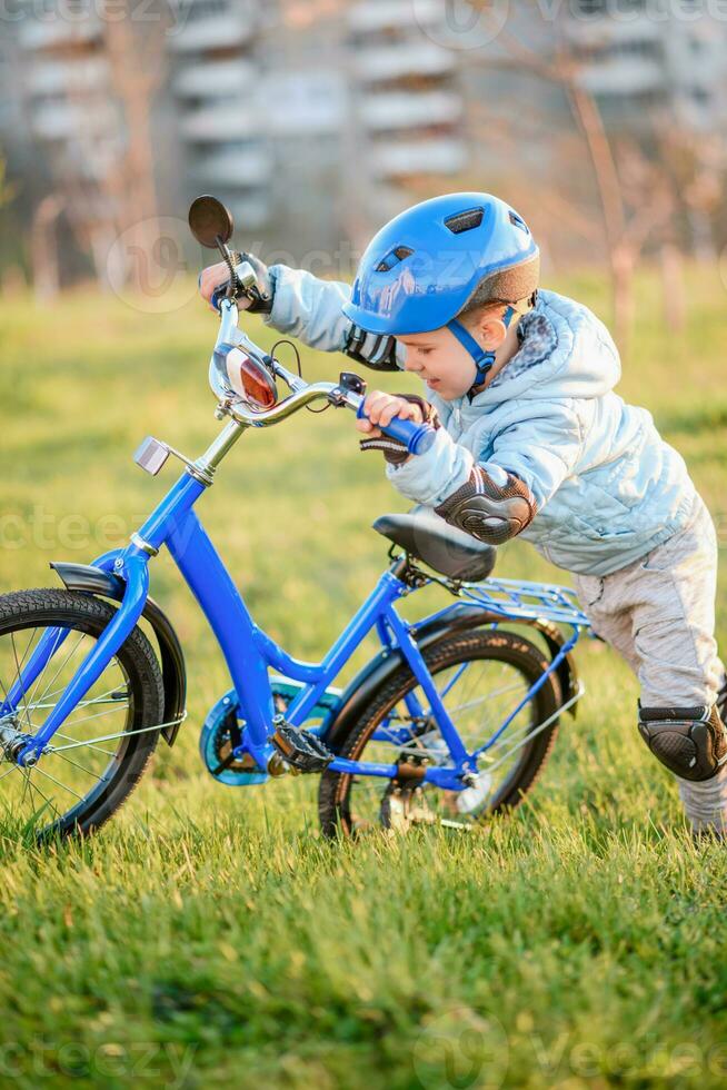 linda niño es conducción un bicicleta en un soleado día a puesta de sol foto