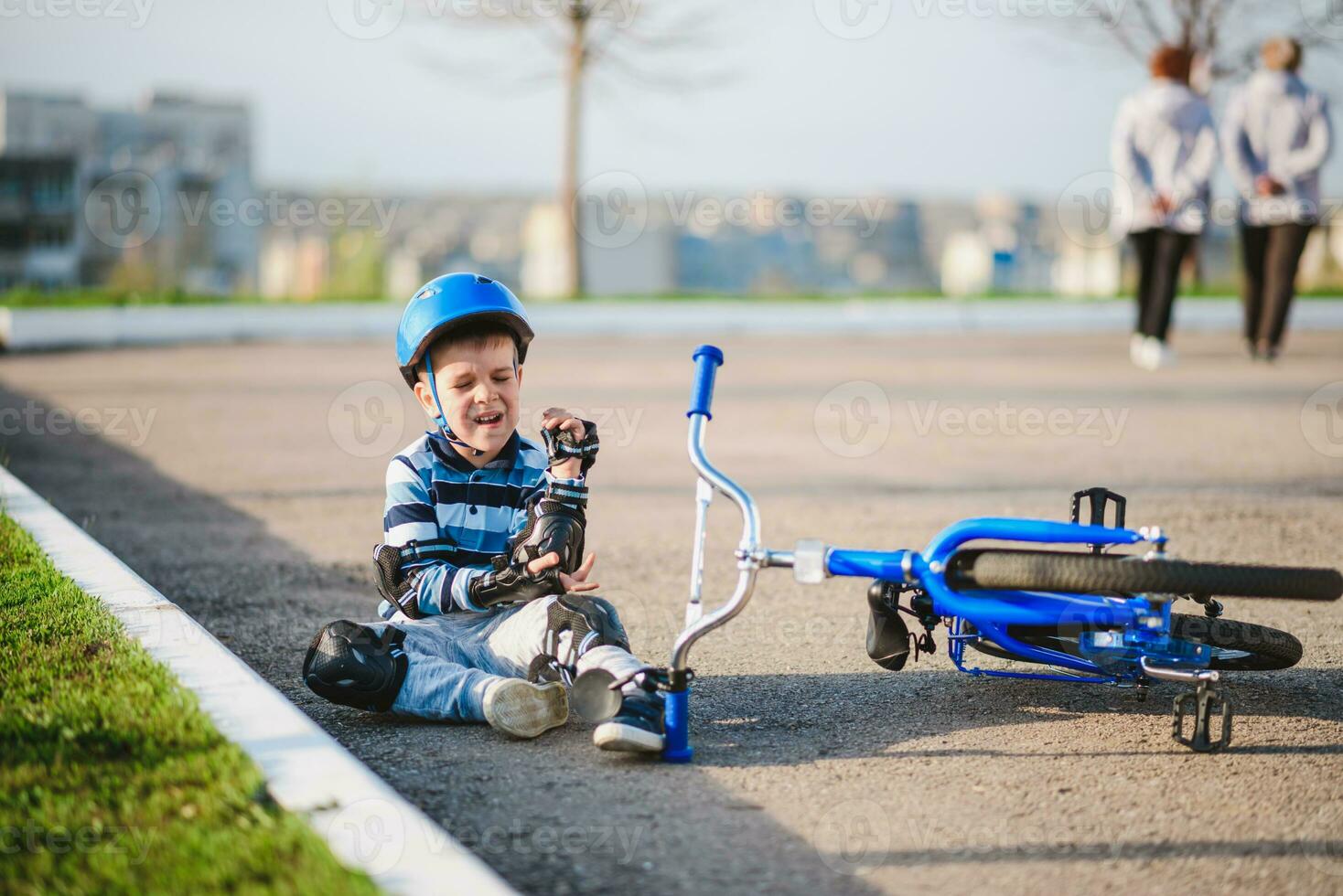 A small child fell from a bicycle onto the road, crying and screaming in pain. photo