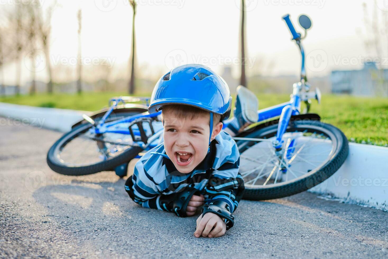 A small child fell from a bicycle onto the road, crying and screaming in pain. photo