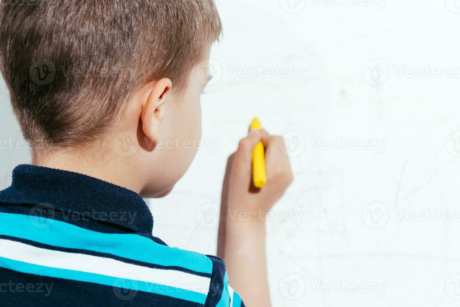 Cute child draws on the wall with colored crayons photo