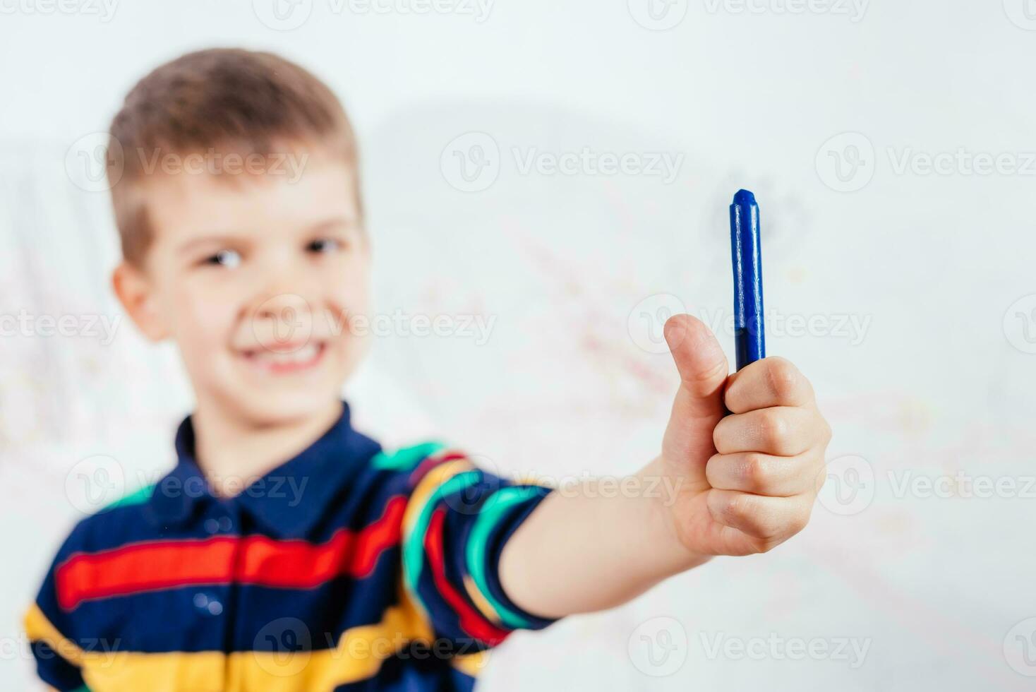 Cute child draws on the wall with colored crayons photo