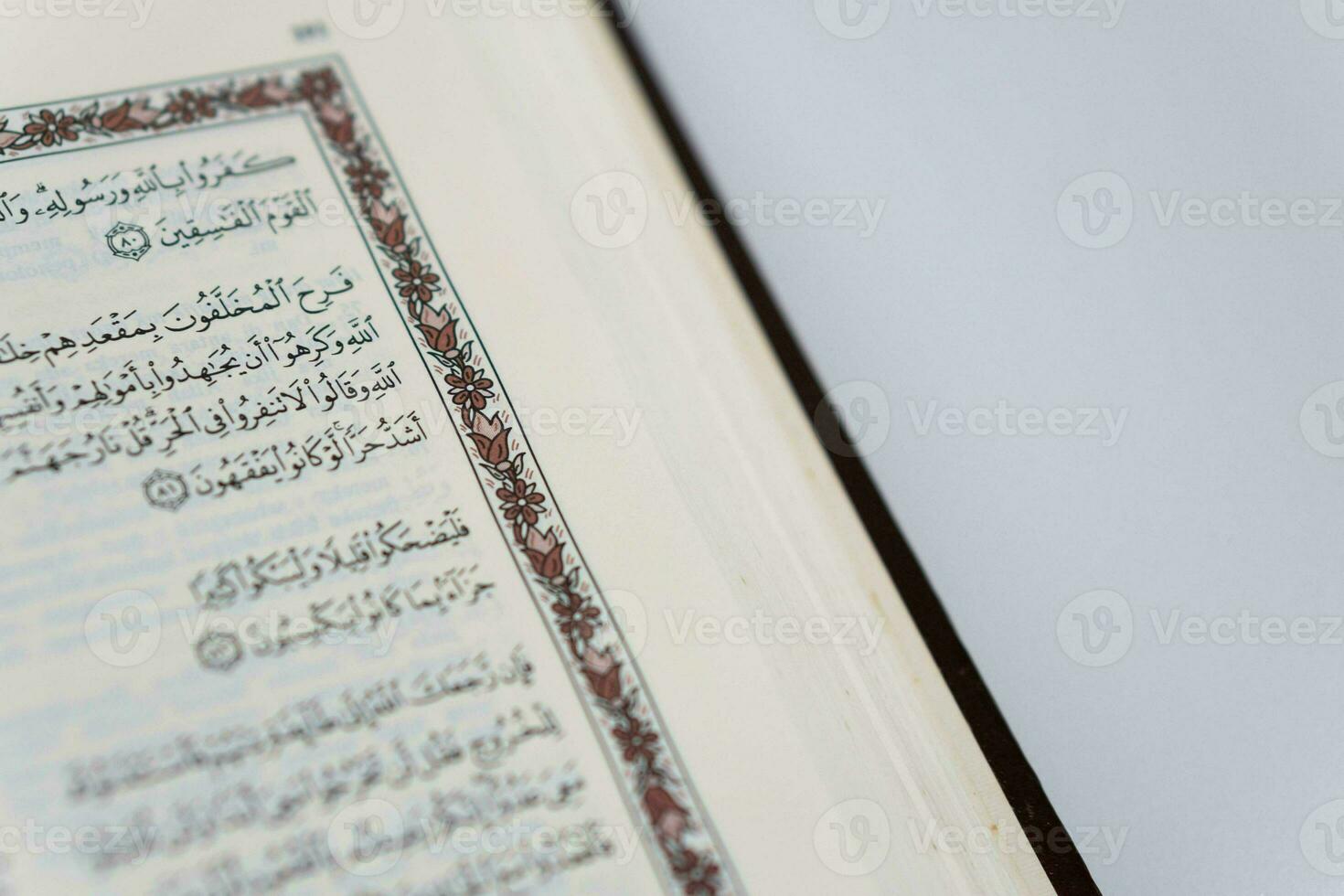 A close up, selective focus view of Arabic script inside the Quran, Koran, or Al Quran, isolated against a white background photo