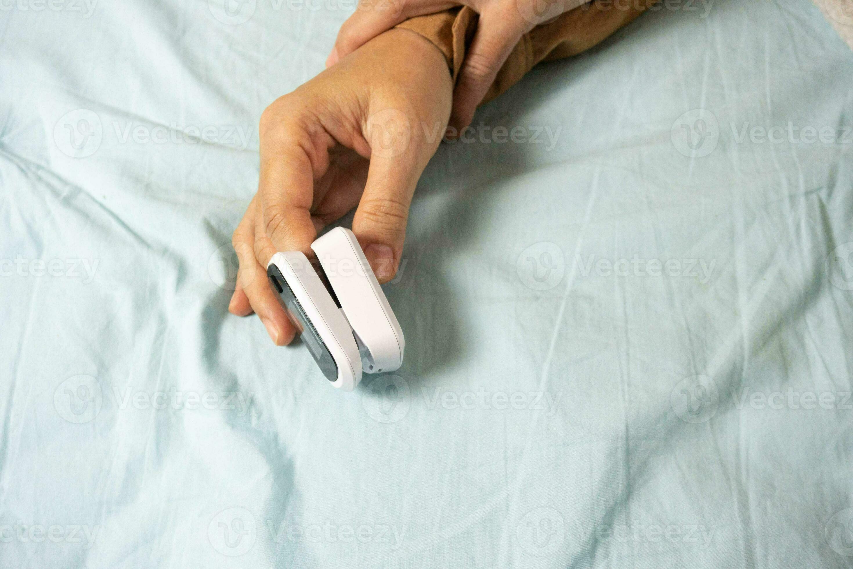Female's hands with a pulse oximeter at the index finger. Woman lying
