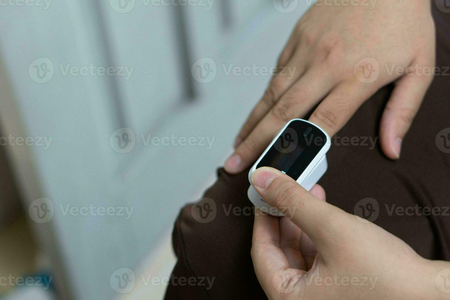 Woman resting at home using pulse oximeter to monitor blood oxygen levels and pulse rate. finger inserted into the pressure oximeter to assess health from the living room home. photo