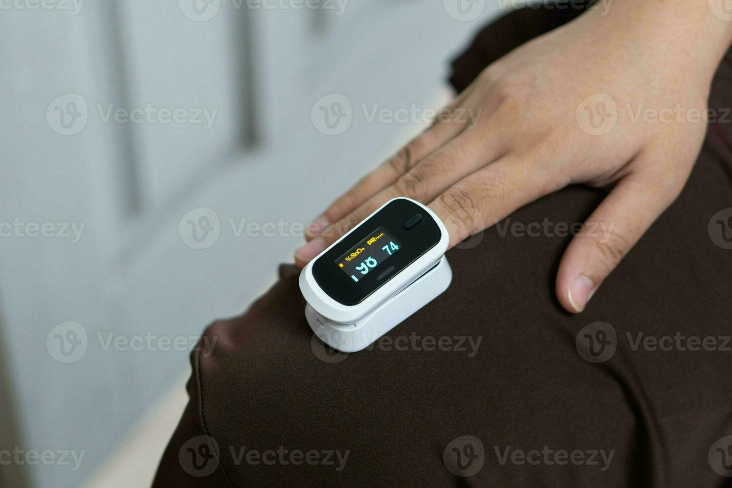 Woman resting at home using pulse oximeter to monitor blood oxygen levels and pulse rate. finger inserted into the pressure oximeter to assess health from the living room home. photo