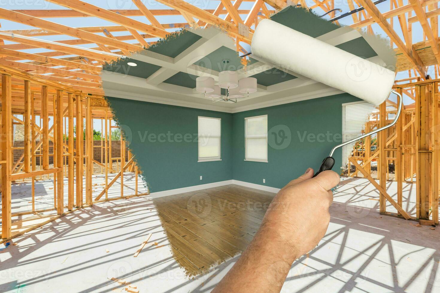 Man Using Paint Roller to Expose Finished Build of House Construction - Before and After. photo