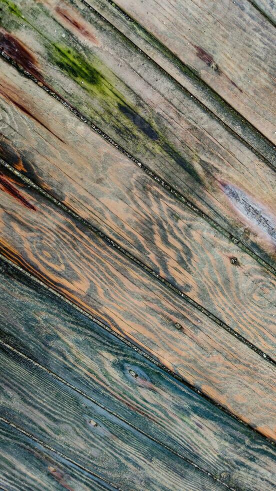 Background of textured wooden surface made of boards with multicolored spots from humidity, diagonal lines, top view, closeup. photo