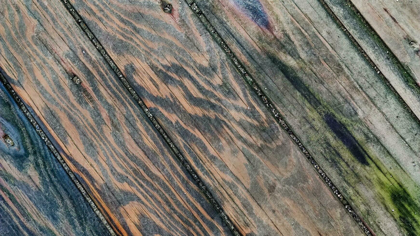 Wooden surface made of boards with multicolored spots from humidity, diagonal lines, top view, closeup. photo