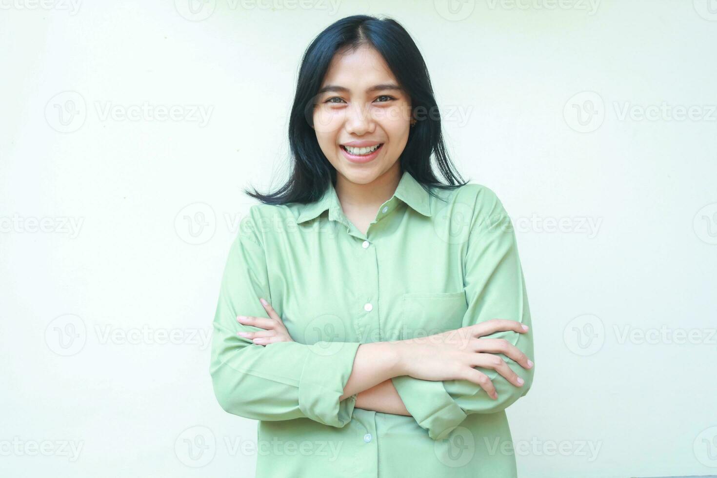 excited confident asian woman hipster smiling at camera with cross hands folding arms wearing green oversized clothes standing over isolated white background photo