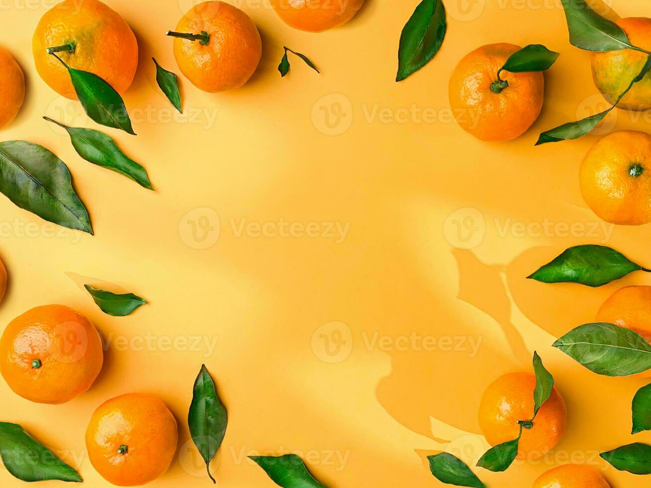 Juicy mandarins with leaves on orange background with openwork shadows free space copy space beautiful frame photo