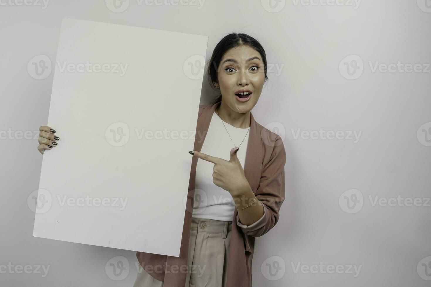 Shocked young Asian woman employee holding empty blank board, isolated by white background photo