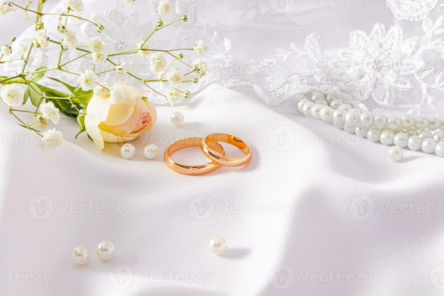 Two gold wedding rings lie on a delicate beige satin background. Bridal bouquet. Design mockup. postcard. invitation. A copy space photo