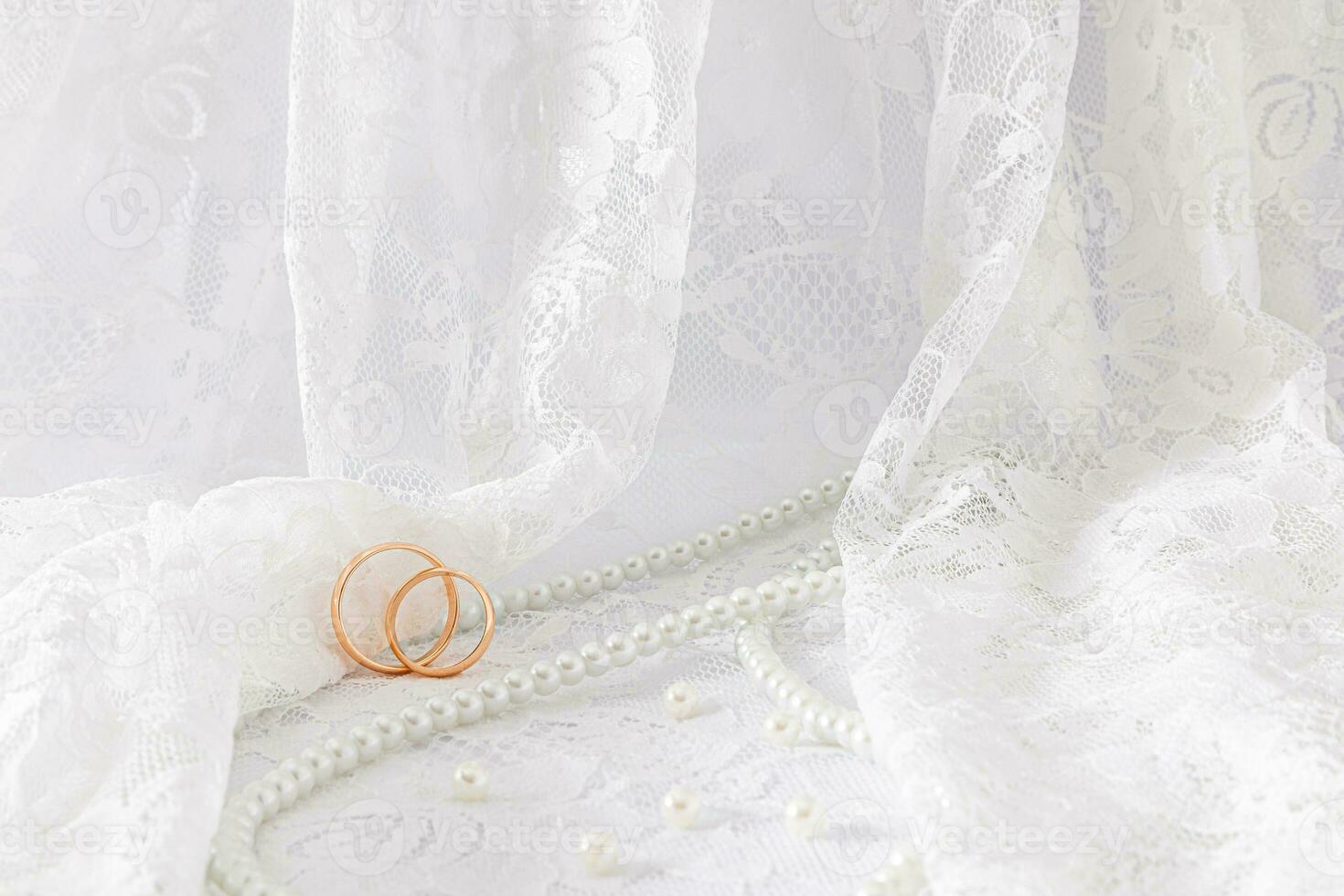 Delicate waves of a wedding veil or tulle with two wedding rings on it. wedding pearl beads of the bride. Front view. A copy of the space. photo