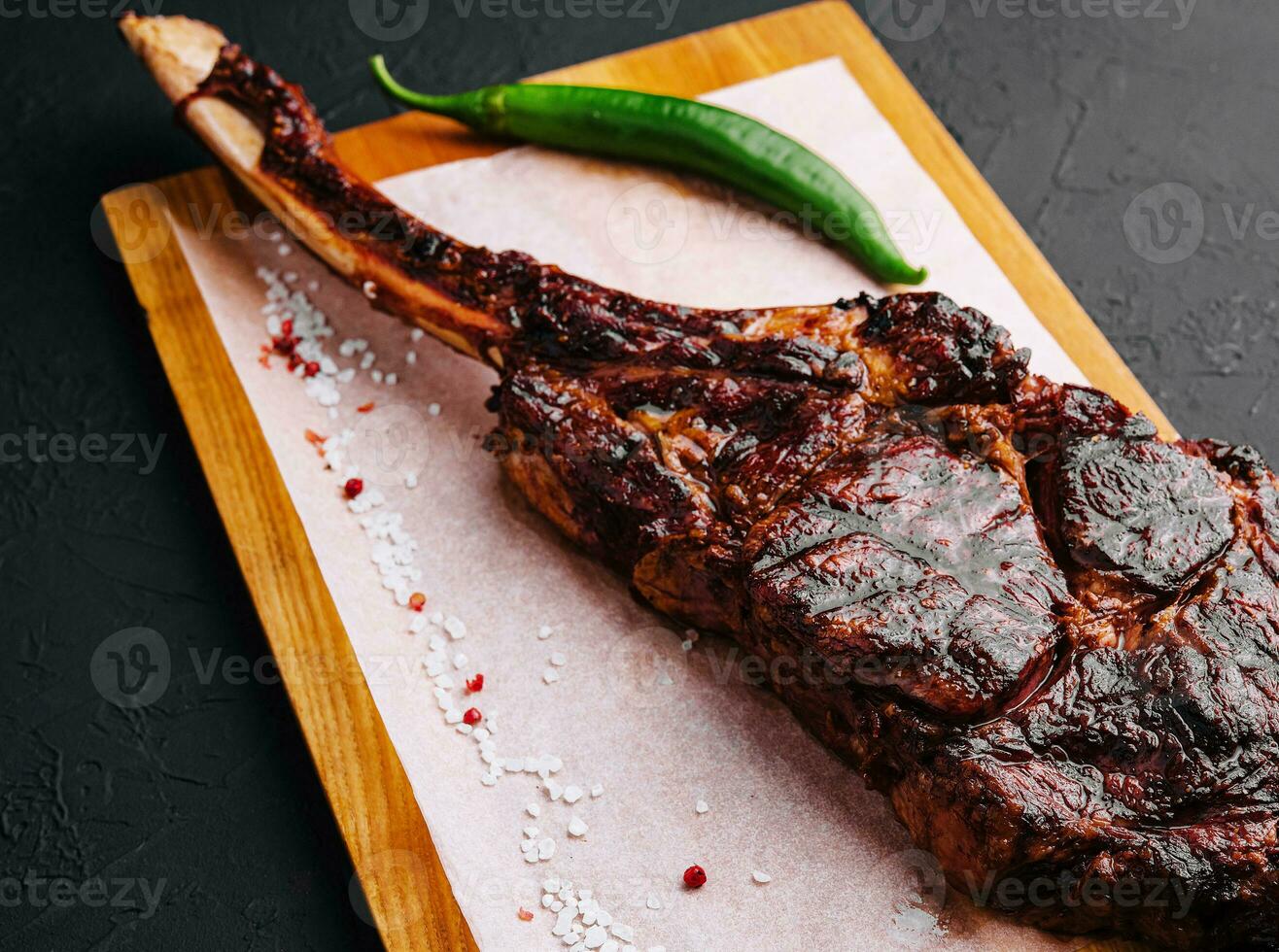 Freshly grilled Tomahawk steak on wooden cutting board photo