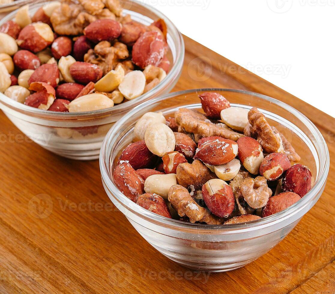 Assorted nuts in a glass bowls on wooden photo