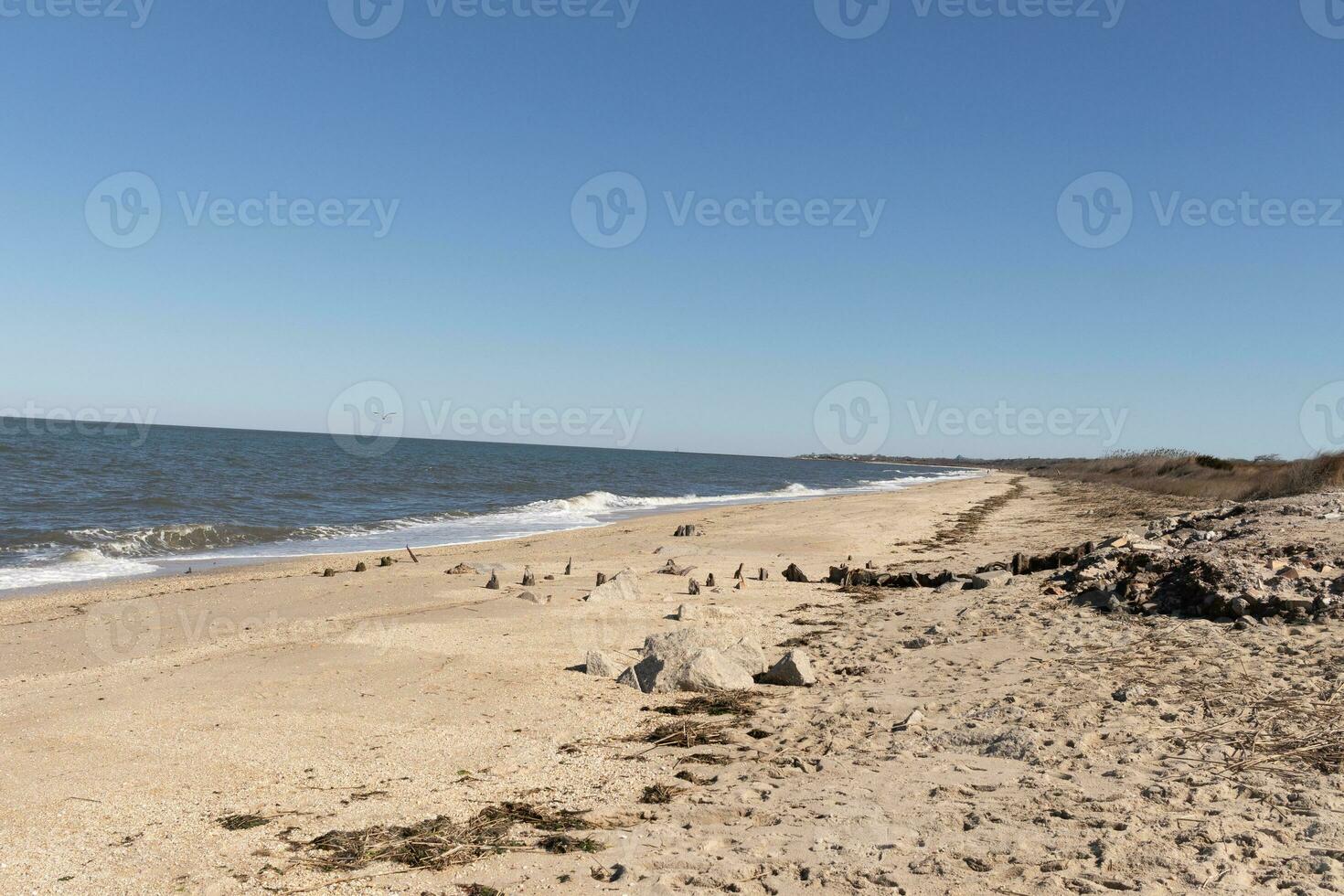 The rocky beach stretches along the shoreline, a rugged mosaic of weathered stones and boulders, sculpted over time by the ceaseless caress of ocean waves. photo