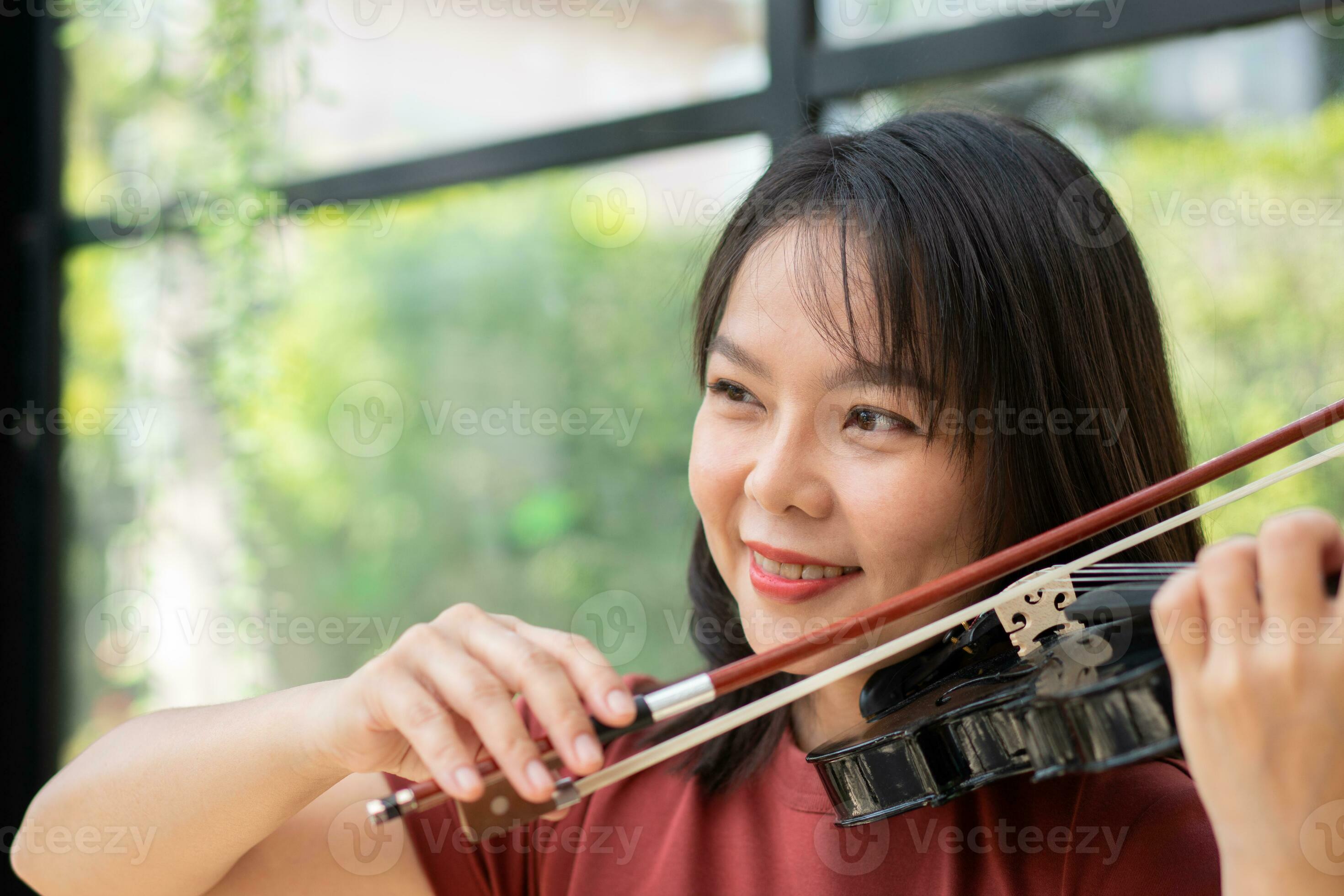 An attractive woman learning musician plays the violin at home