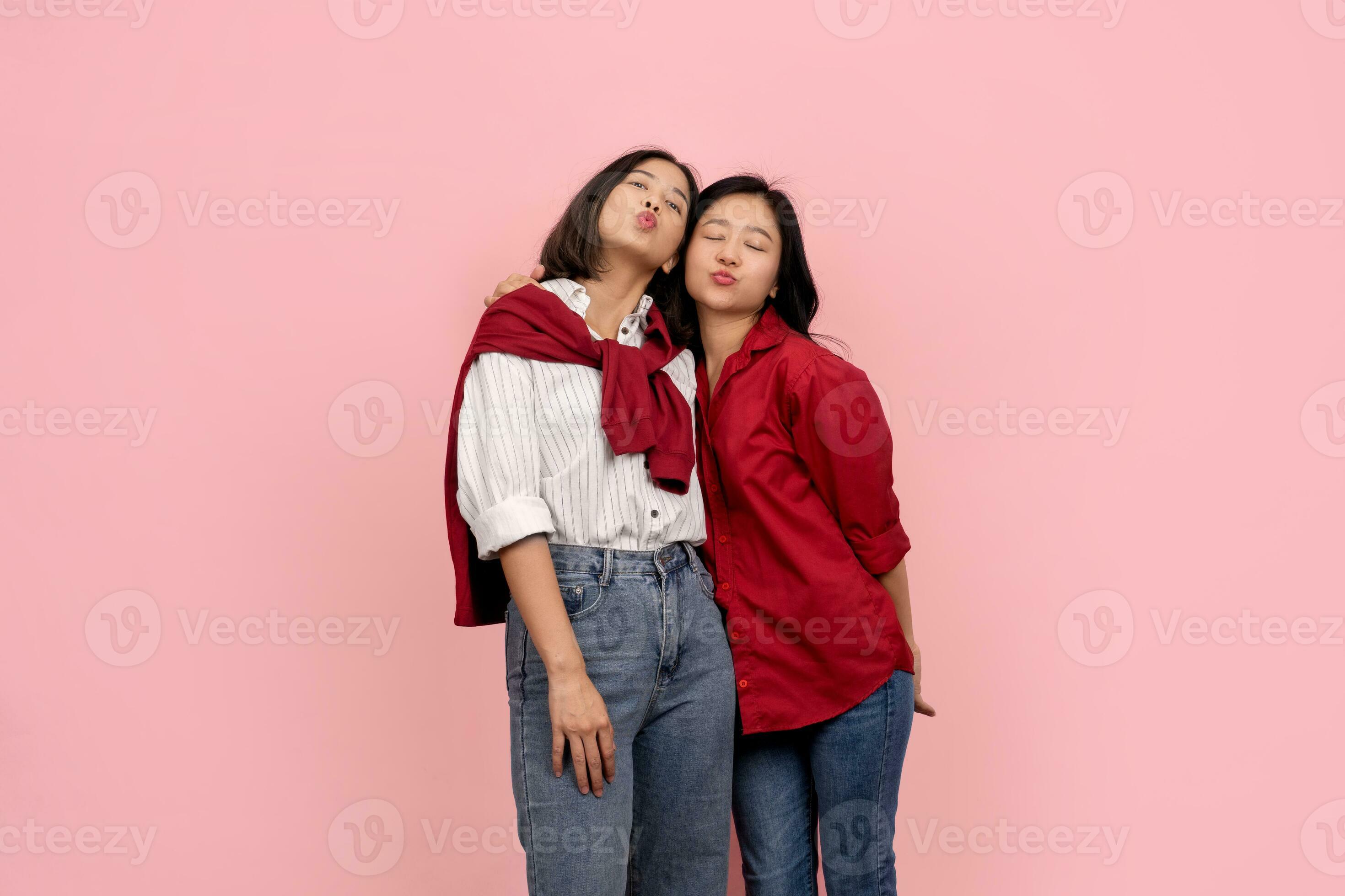 Happy Asian Lesbian Couple Blowing A Kiss At The Camera On A Pink Background Love Concept