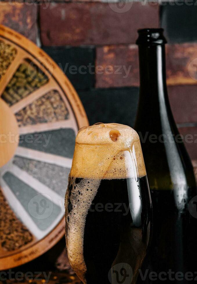 Glass of dark beer and bottle on wooden photo