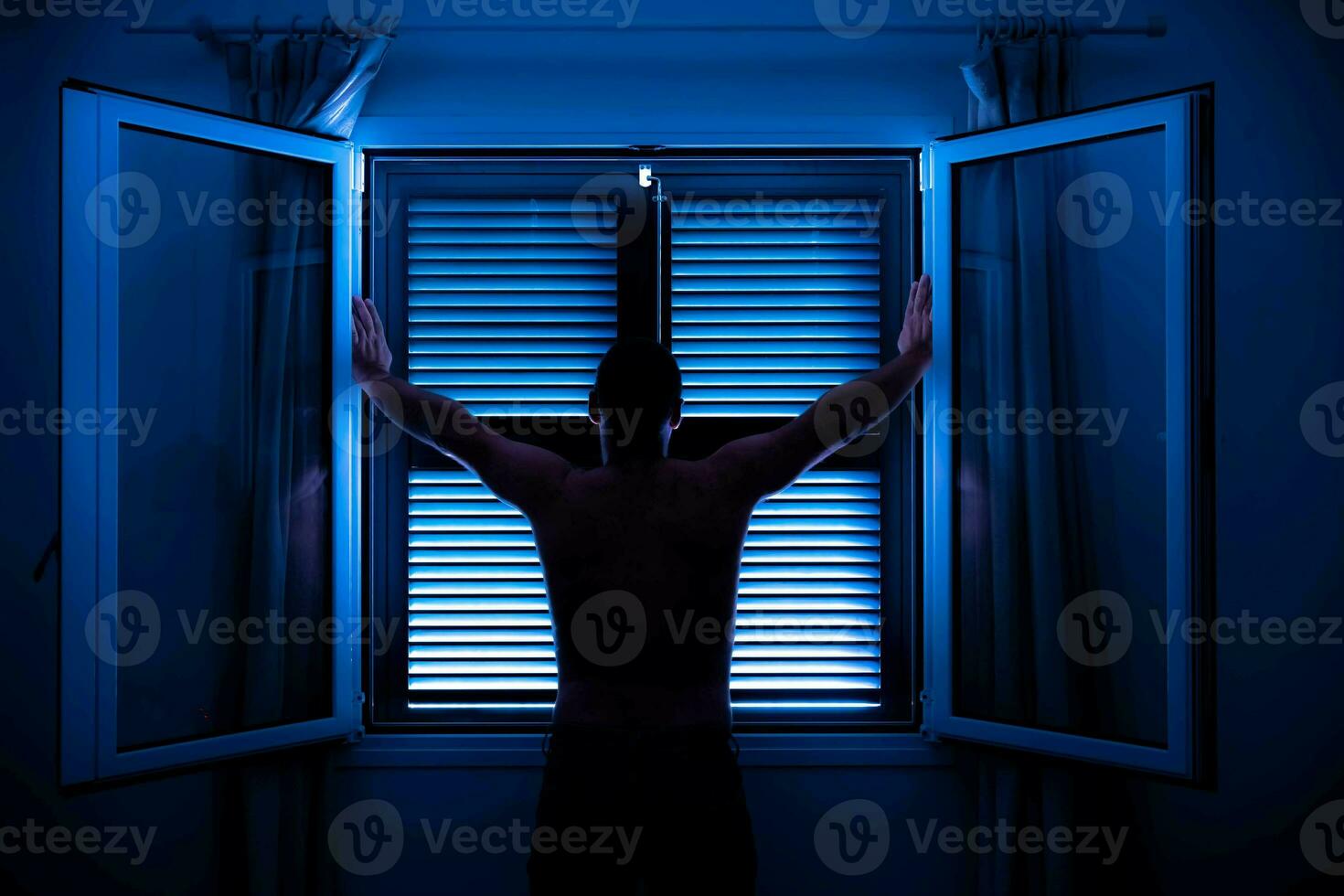 unrecognizable man face up with arms raised in front of window photo