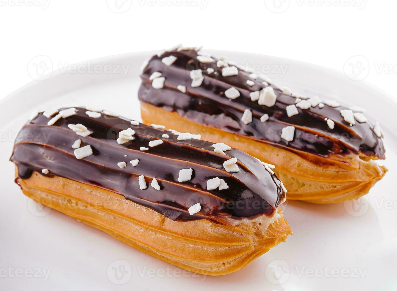 Two eclairs with chocolate glaze in white plate photo