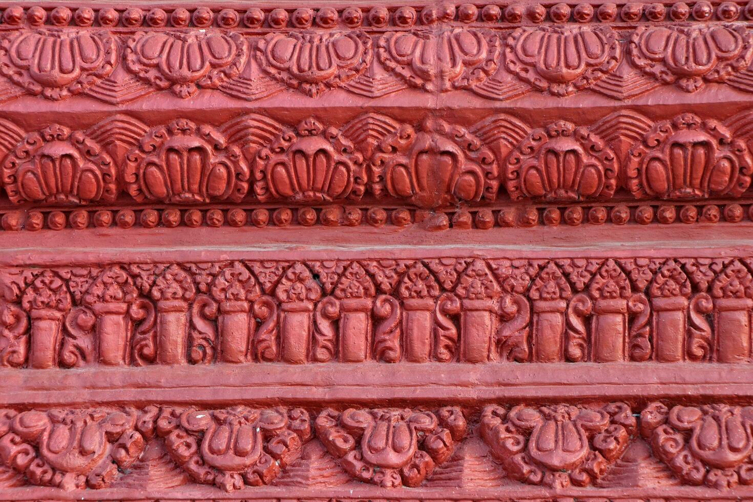 The concrete walls are painted in red and have simple carved patterns. photo