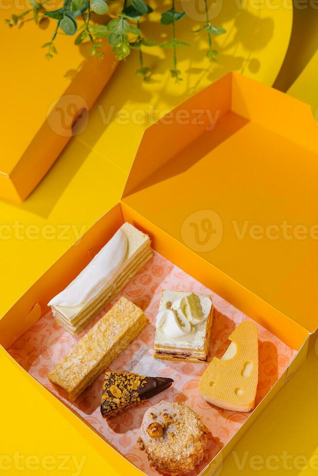 Assorted Cake Slices in Yellow Gift Box on Yellow Background photo