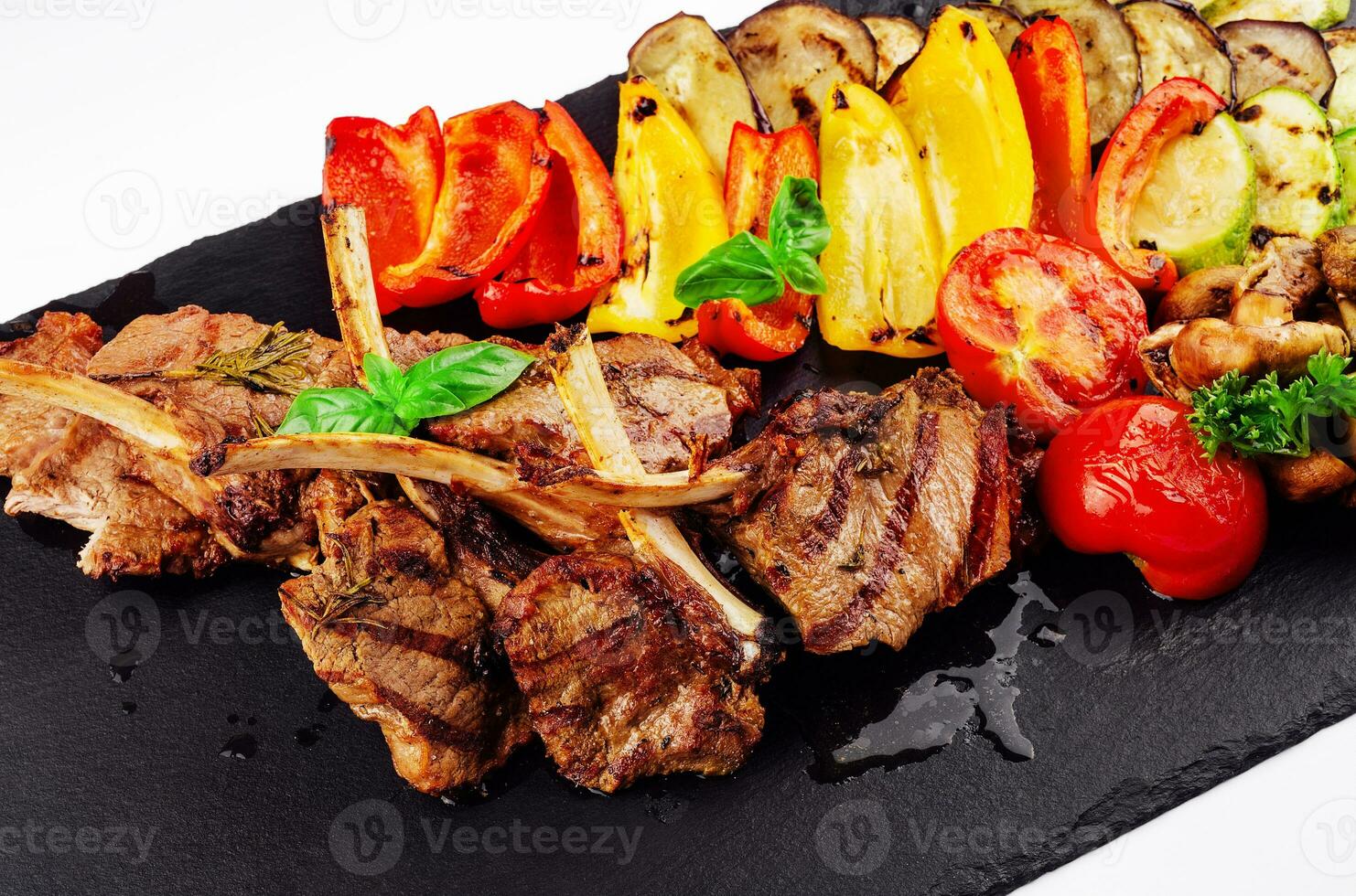 Grilled lamb chops with vegetables on a stone board photo