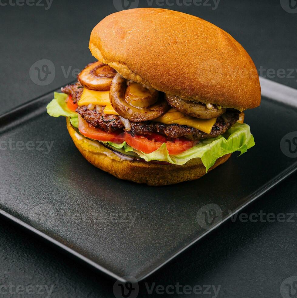 Burger with mushrooms and cutlet on black tray photo