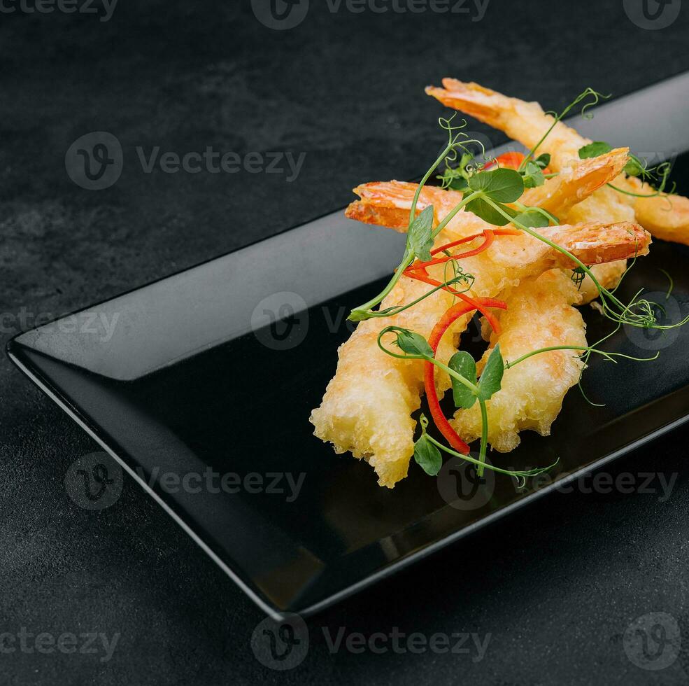 Fried shrimps tempura with sweet chili sauce on black stone plate photo