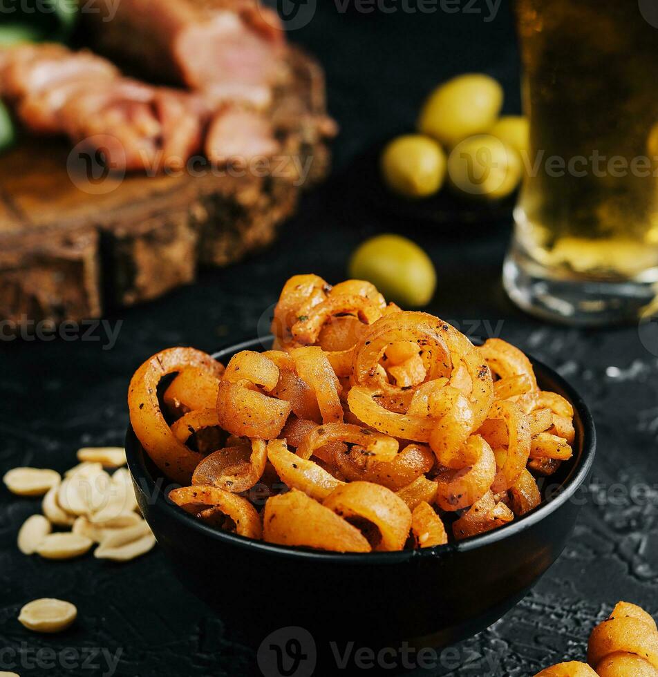 Pork ear snack in the bowl close up with beer in a glass photo