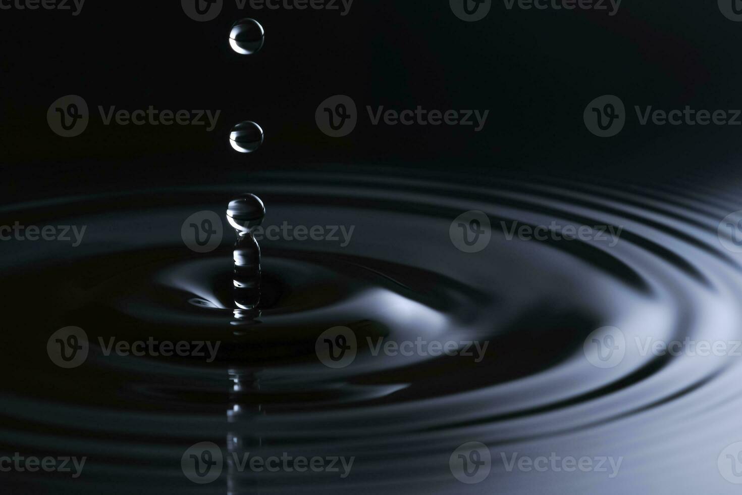 Water drops hitting the clean surface of the water close-up. photo