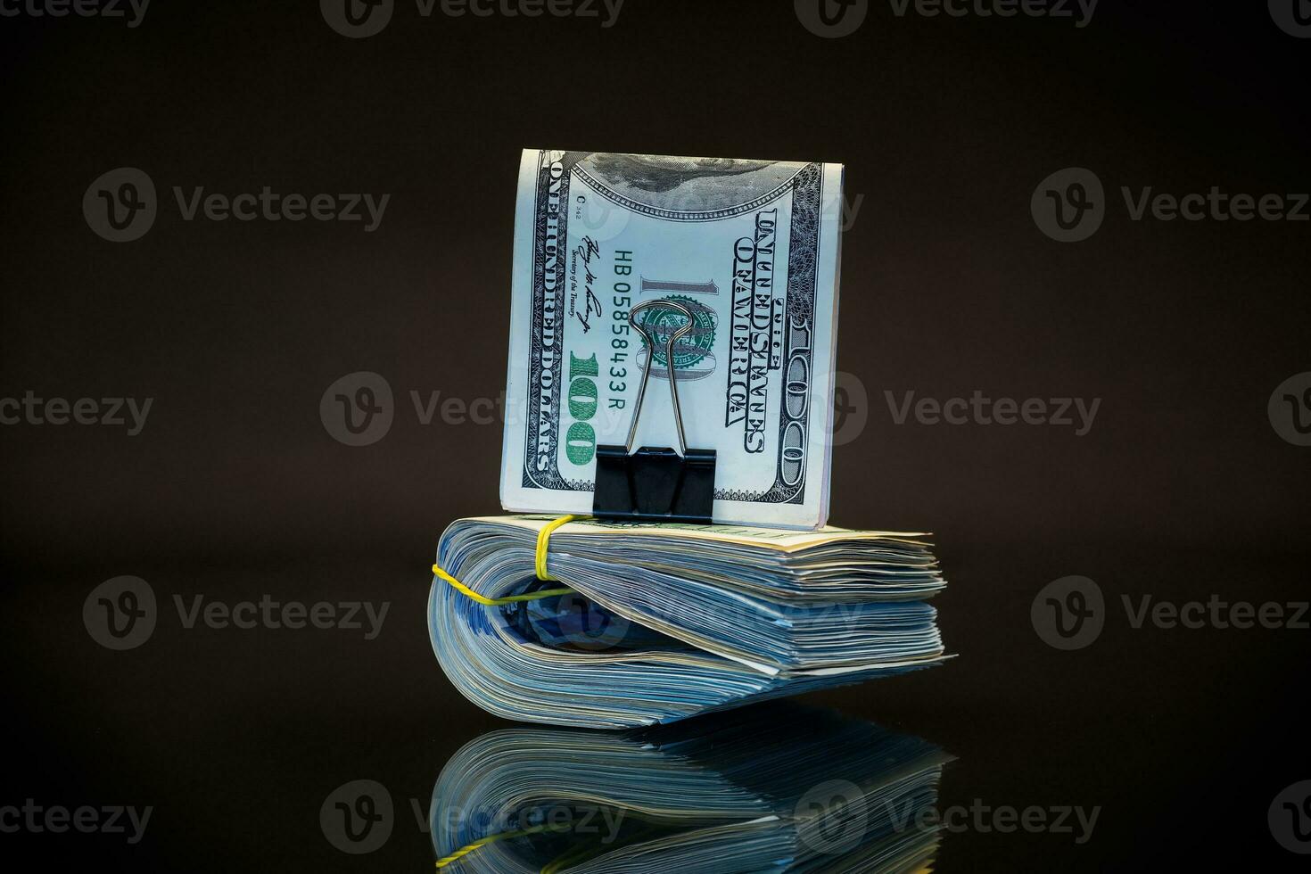 stack of dollar bills collected in an elastic band and a stationery clip photo