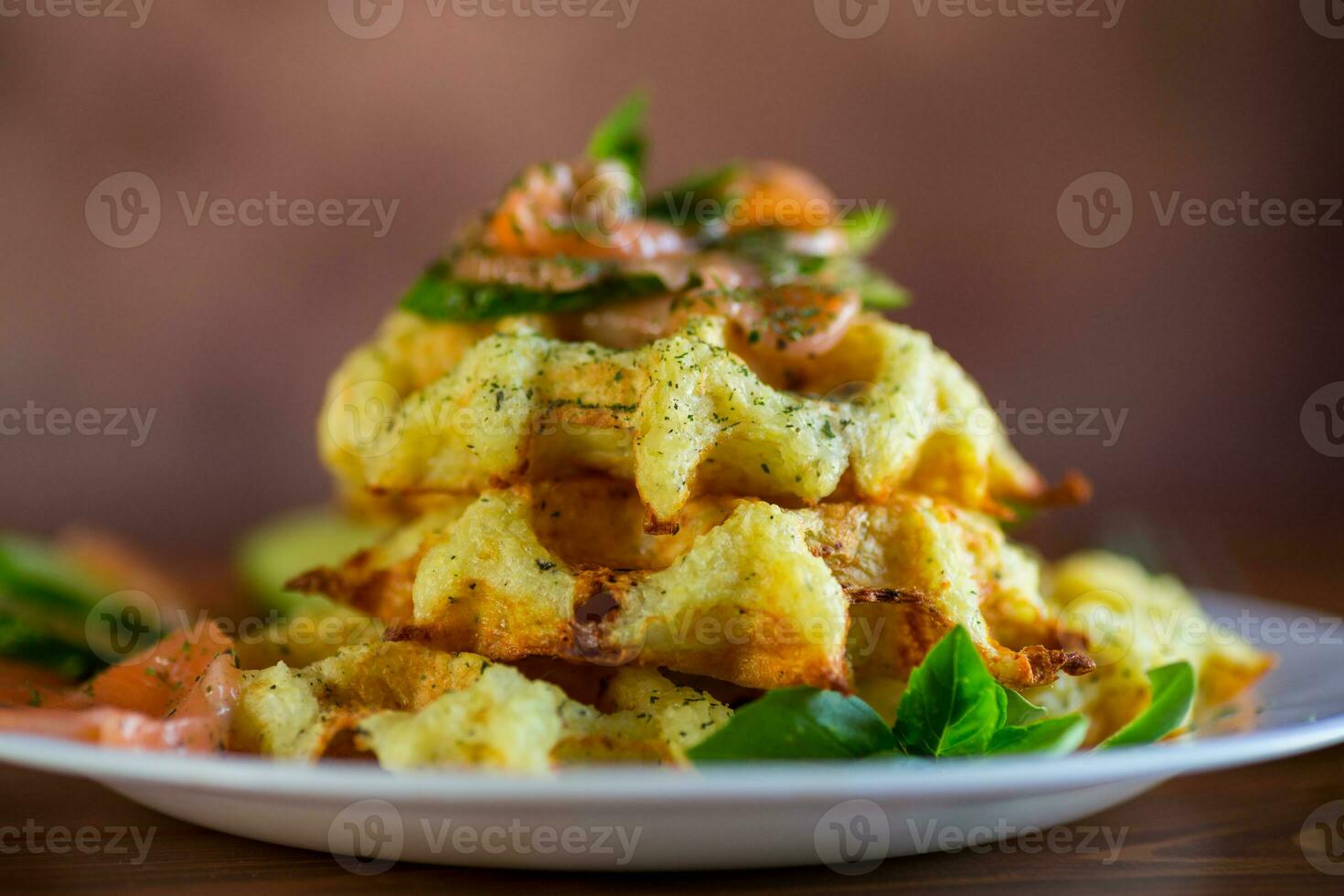 Cooked potato waffles with lightly salted red fish and herbs in a plate. photo