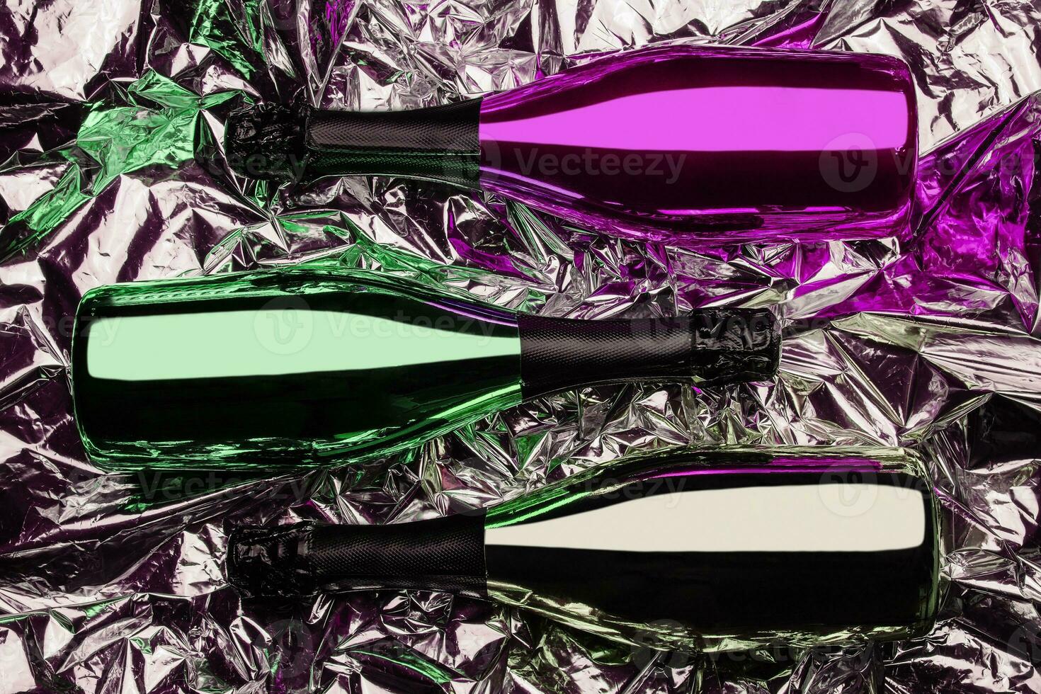 three different bottles of champagne on foil background photo