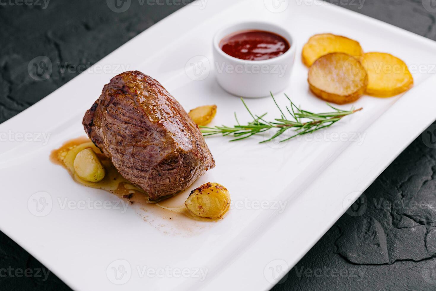 fried medallion with garlic, potatoes and rosemary photo
