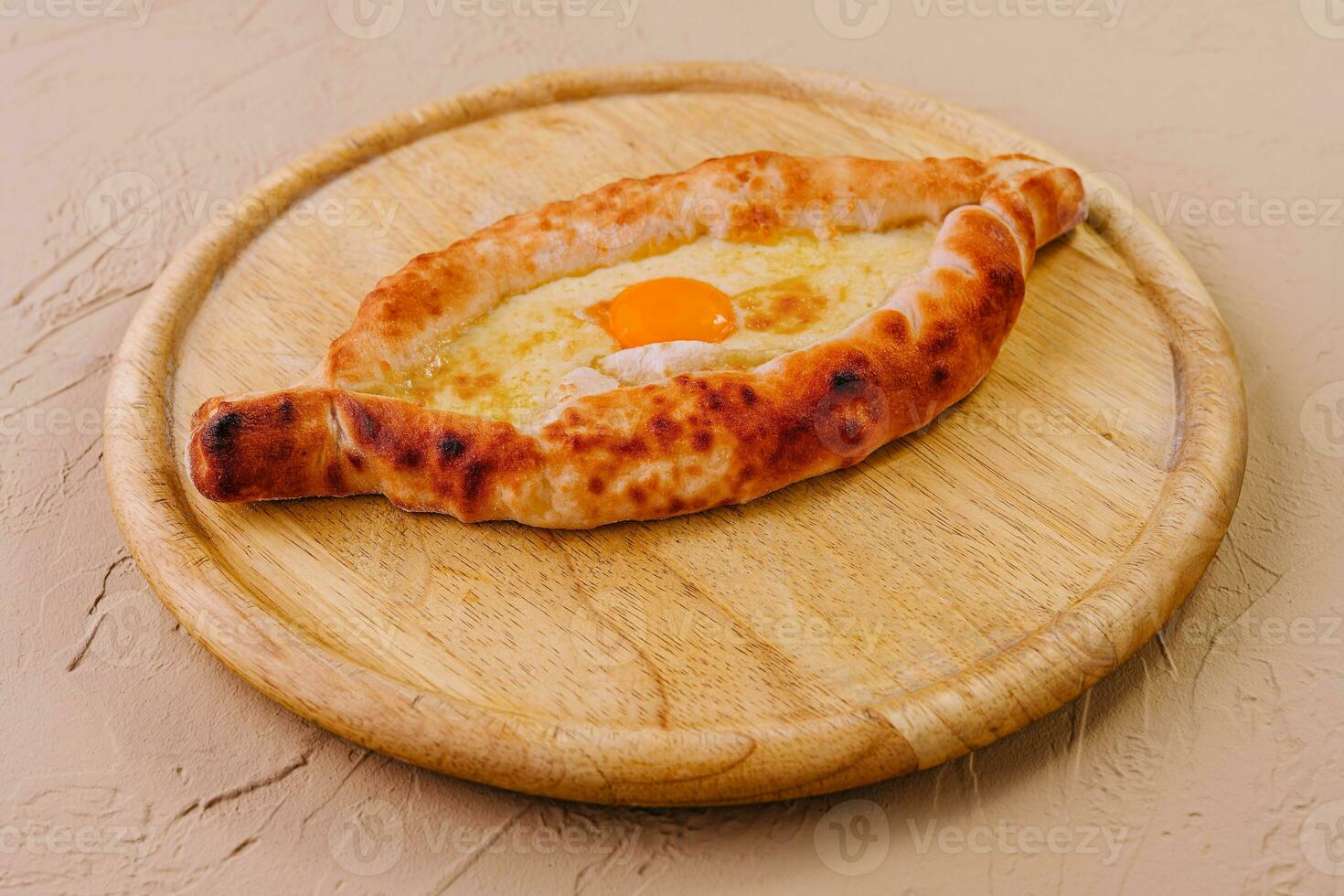 Ajarian Khachapuri, filled with cheese and topped with egg yolk photo