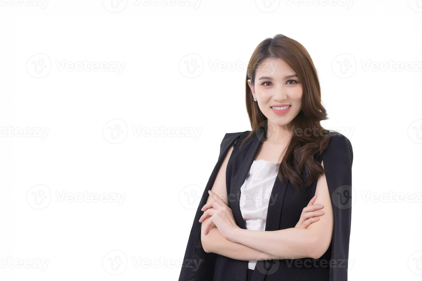 Young beautiful asian professional businesswoman standing with crossed arms in office workspace while looking at camera while isolated on white background. photo